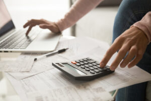 person typing on a laptop and using a calculator